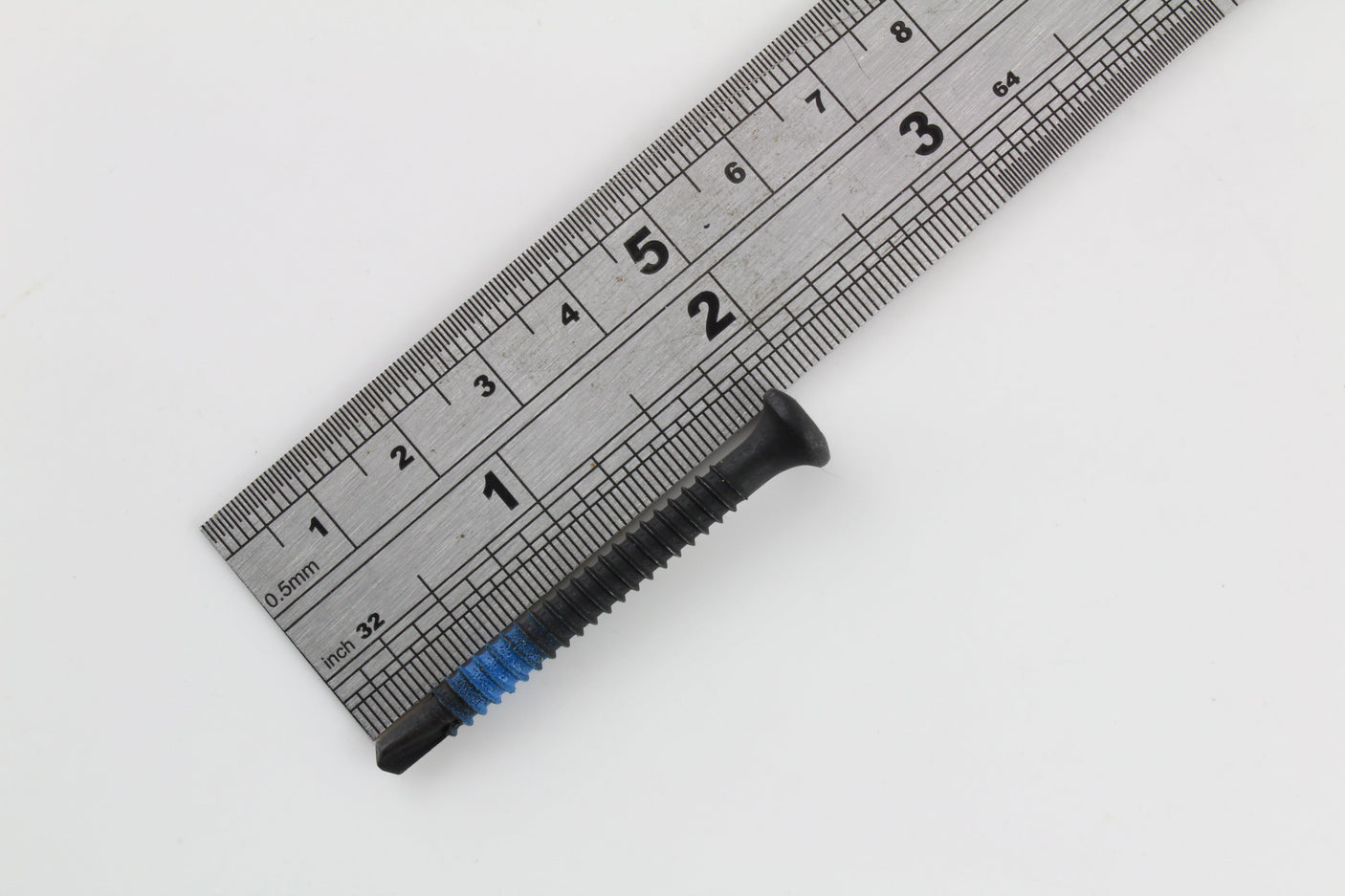 Single blue-banded Lokko plug puller screw measured against a steel ruler at about four centimetres