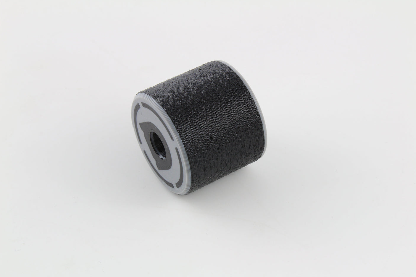 Bump key dampener lying on its side showing the grey threaded cap face and textured rubber body