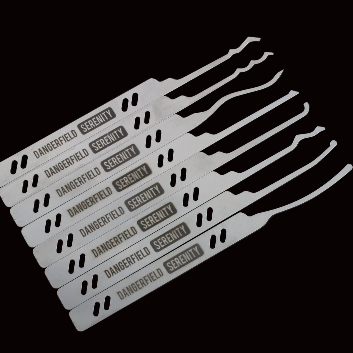 Six white metal lock pick tools with black text reading 'DANGERFIELD SECURITY' and diagonal black dash patterns, arranged on a dark background.