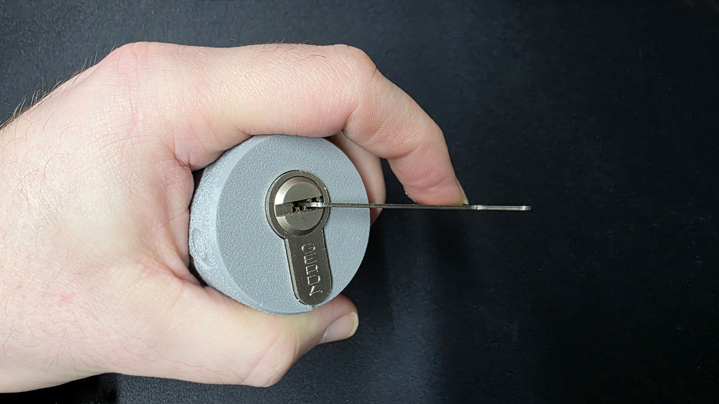 Hand cradling the Lokko euro cylinder support with a tension wrench set in the keyway ready to pick