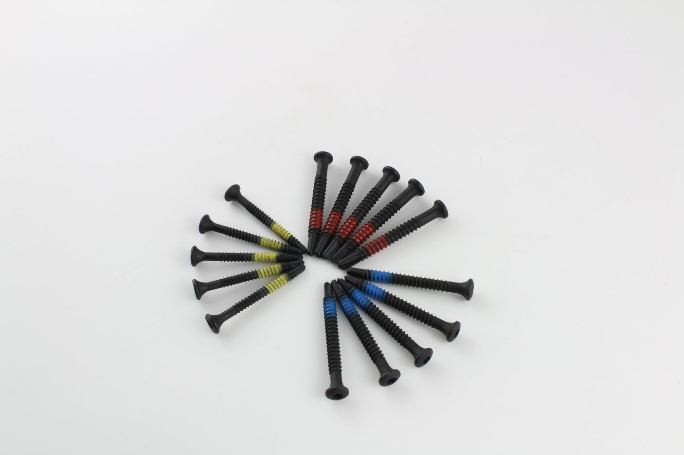 Colour-coded Lokko extraction screws arranged in a circle on a pale studio background