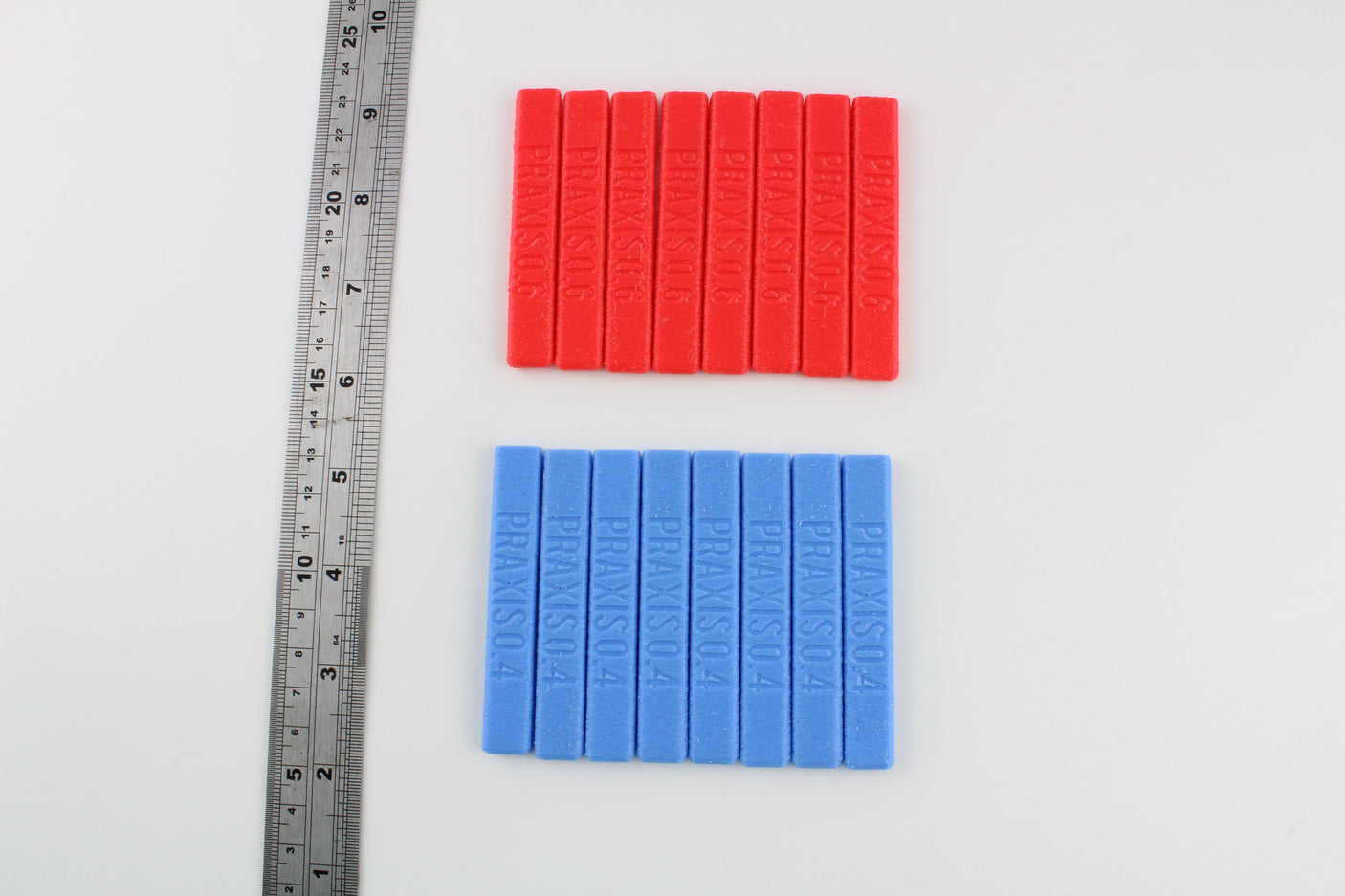 Dangerfield Praxis grip handles beside a steel ruler, red 0.6 and blue 0.4 handles shown for scale