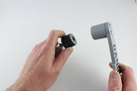 Hand holding a bump key in the rubber dampener next to the grey Dangerfield bump hammer