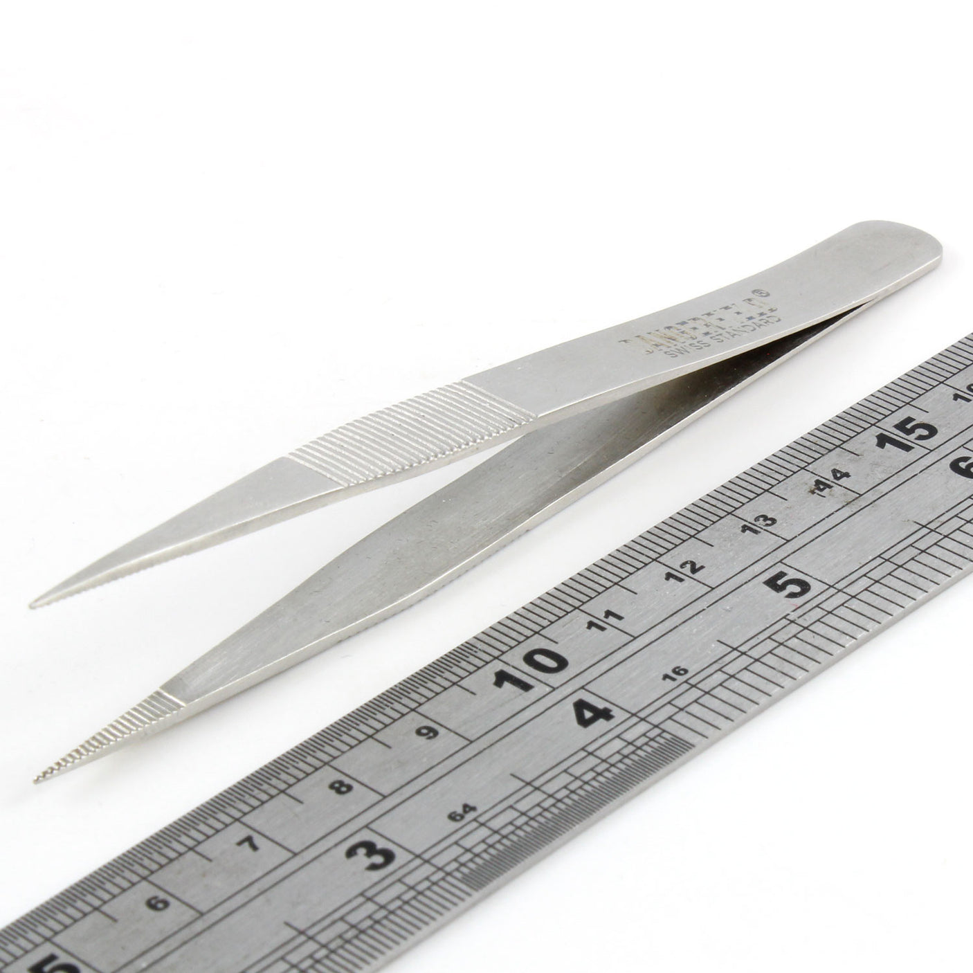 Dangerfield repinning tweezers at an angle beside a ruler for scale