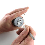 One hand cradling the Lokko support with a euro cylinder inside while the other hand picks the keyway with a tension wrench seated