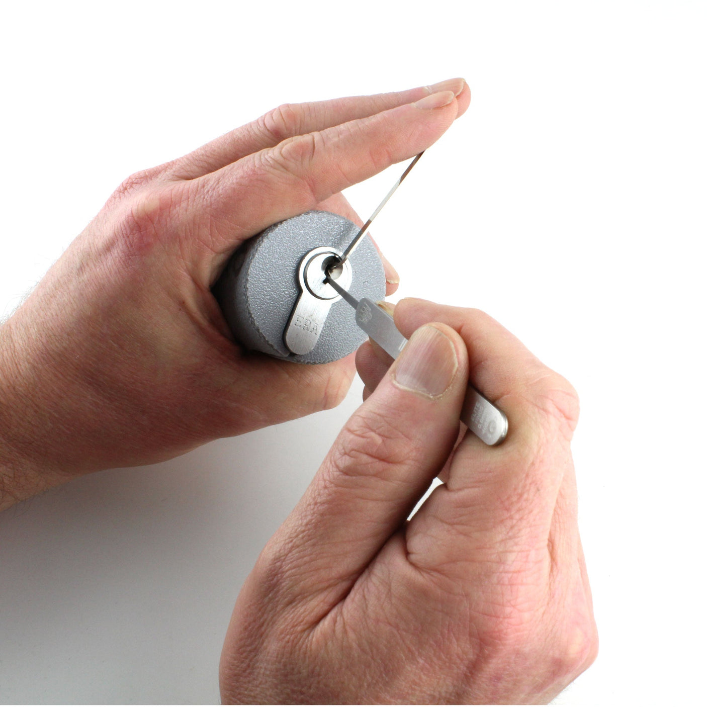 Hands working a euro cylinder held in the Lokko support, pick in the keyway and tension wrench in the bottom