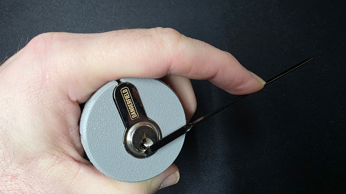 Hand holding the Lokko support with a euro cylinder inside and a Dangerfield tension wrench seated in the keyway